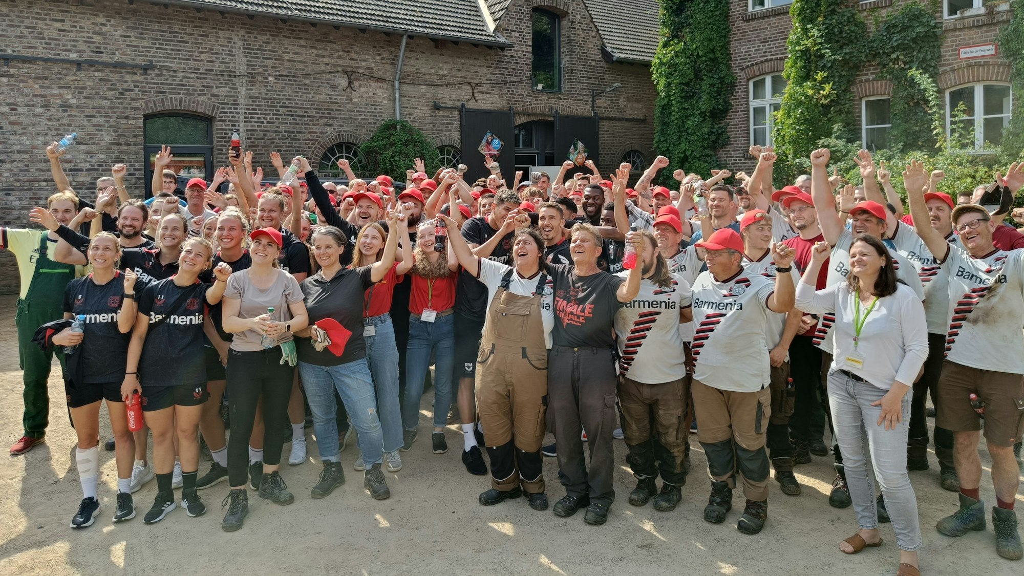 Eine Vielzahl an Menschen mit hochgerissenen Armen und glücklichen Gesichtern.