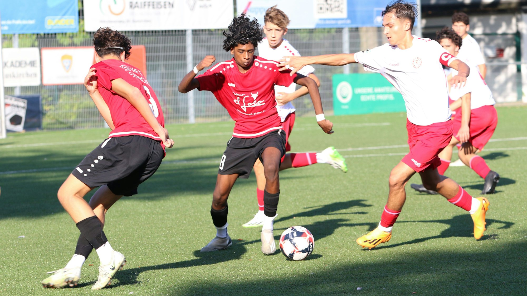 Ein Euskirchener Spieler im roten Trikot will dribbeln, der Fortuna-Kapitän greift mit ausgestrecktem Arm nach ihm.
