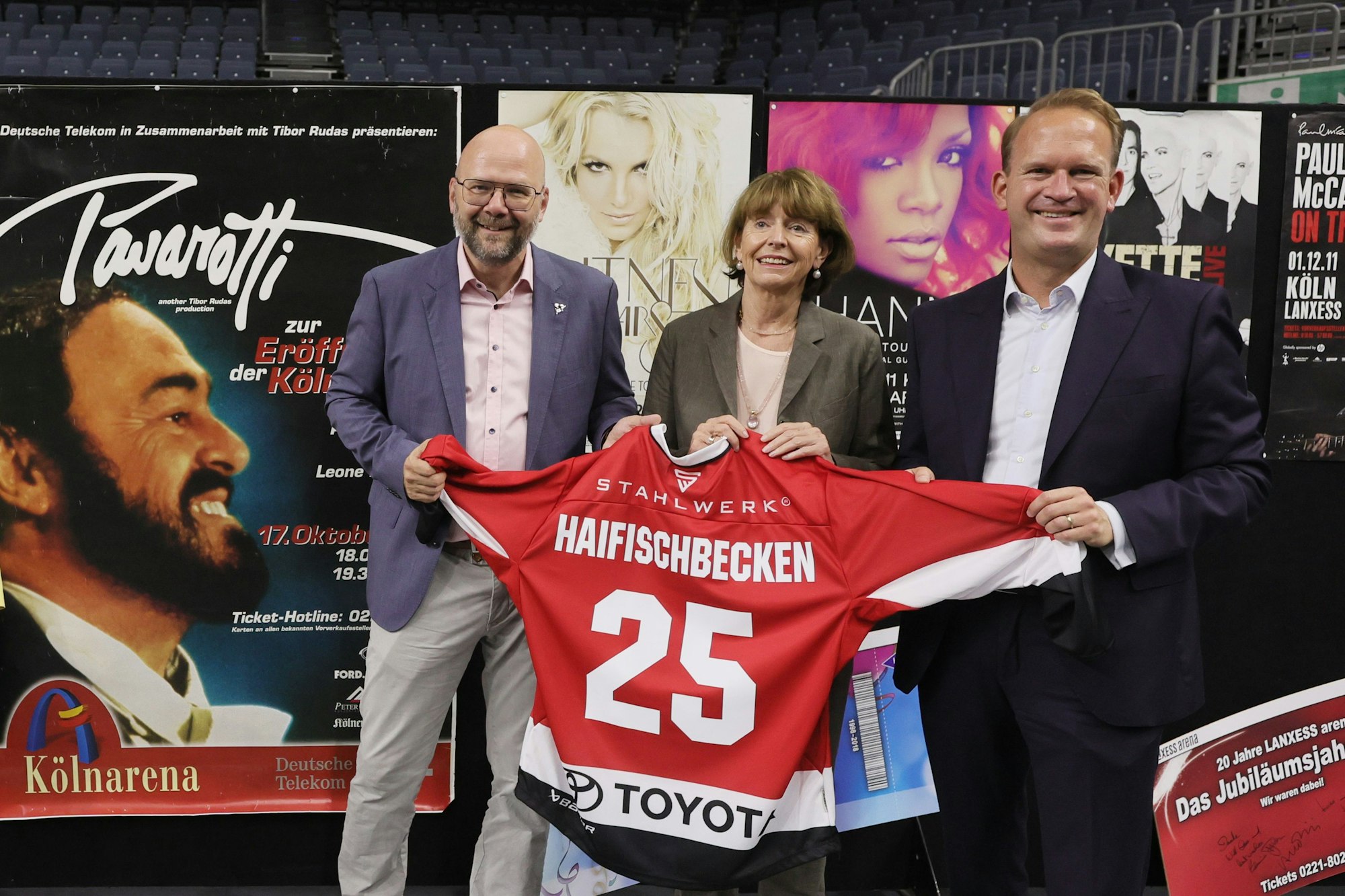 Philipp Walter, Henriette Reker und Stefan Löcher halten ein Eishockey-Trikot in den Händen.