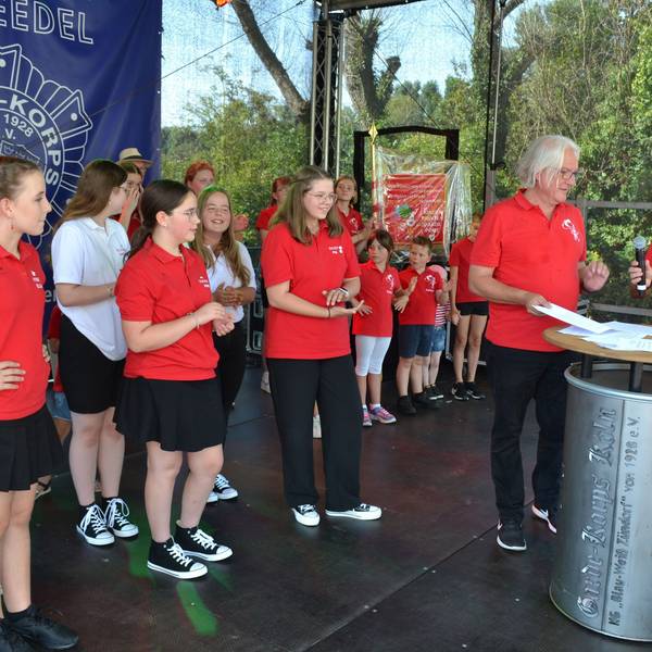 Das designierte Porzer Kinderdreigestirn in den roten Polo-Shirts um Ella Reichen (v.l.), Marie Röhrig und Pia Immendorf wartet darauf, die Unterschrift unter den Vertrag zu setzen.