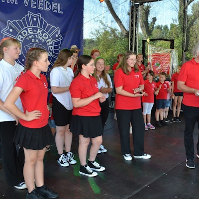Das designierte Porzer Kinderdreigestirn in den roten Polo-Shirts um Ella Reichen (v.l.), Marie Röhrig und Pia Immendorf wartet darauf, die Unterschrift unter den Vertrag zu setzen.