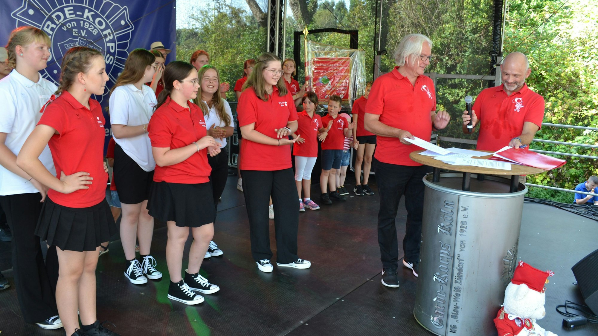 Das designierte Porzer Kinderdreigestirn in den roten Polo-Shirts um Ella Reichen (v.l.), Marie Röhrig und Pia Immendorf wartet darauf, die Unterschrift unter den Vertrag zu setzen.