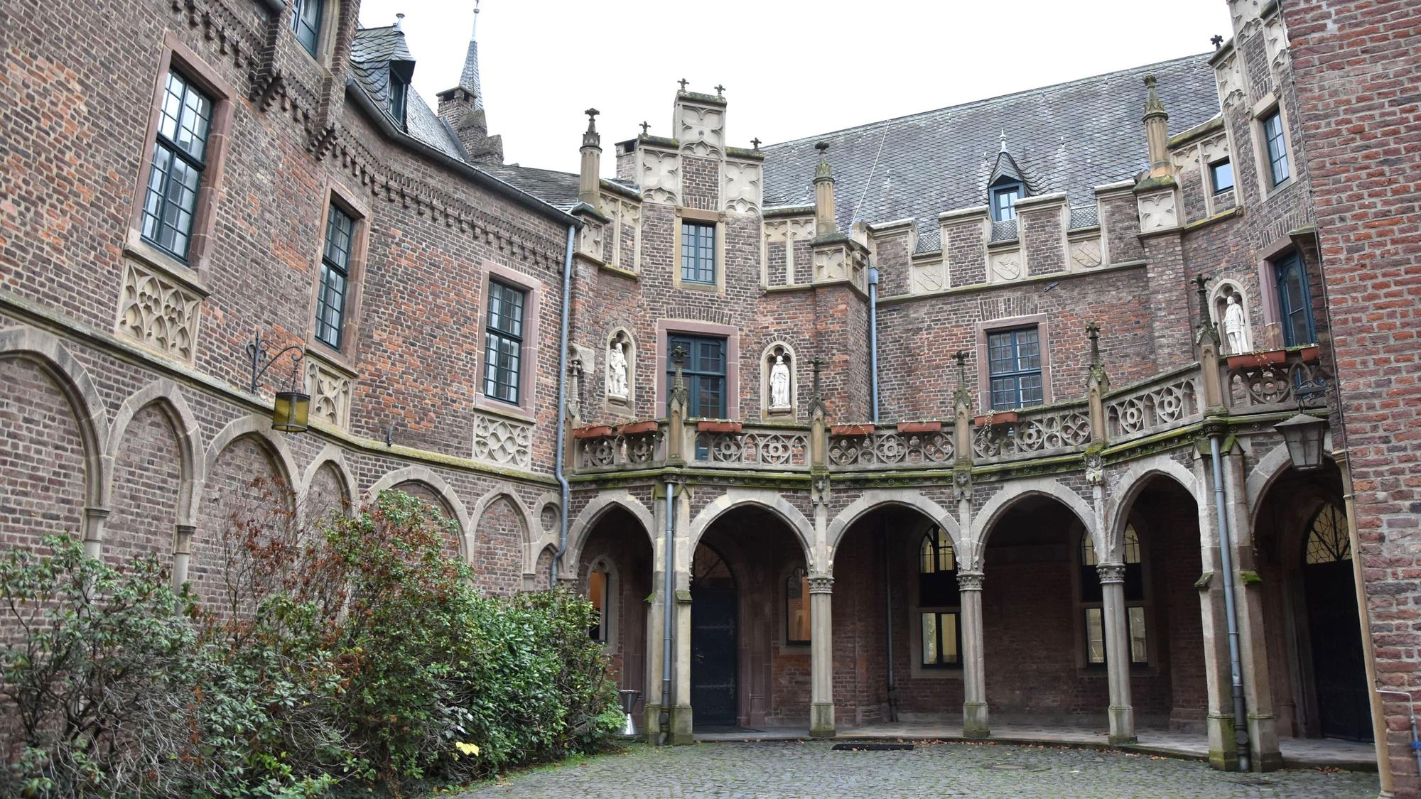 Das Schloss Paffendorf ist zu sehen, mit Rundbögen, Glasfenstern und einem Teil eines Innenhofs.