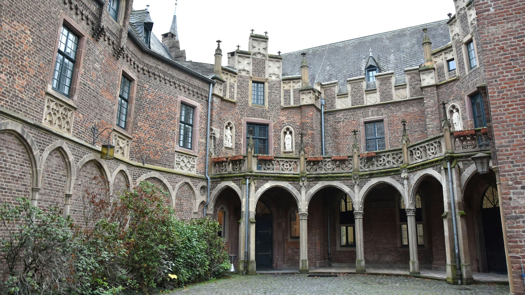 Das Schloss Paffendorf ist zu sehen, mit Rundbögen, Glasfenstern und einem Teil eines Innenhofs.