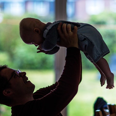 Ein junger Vater spielt mit seinem sechs Monate alten Sohn im Wohnzimmer.