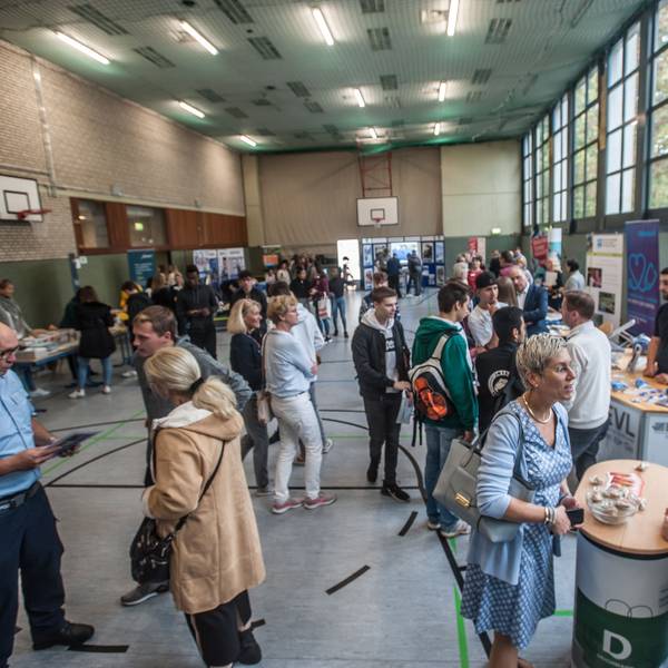 Ausbilder und Azubis stehen am Tag der Bewerbung 2019 in der Sporthalle des Berufskollegs Opladen.