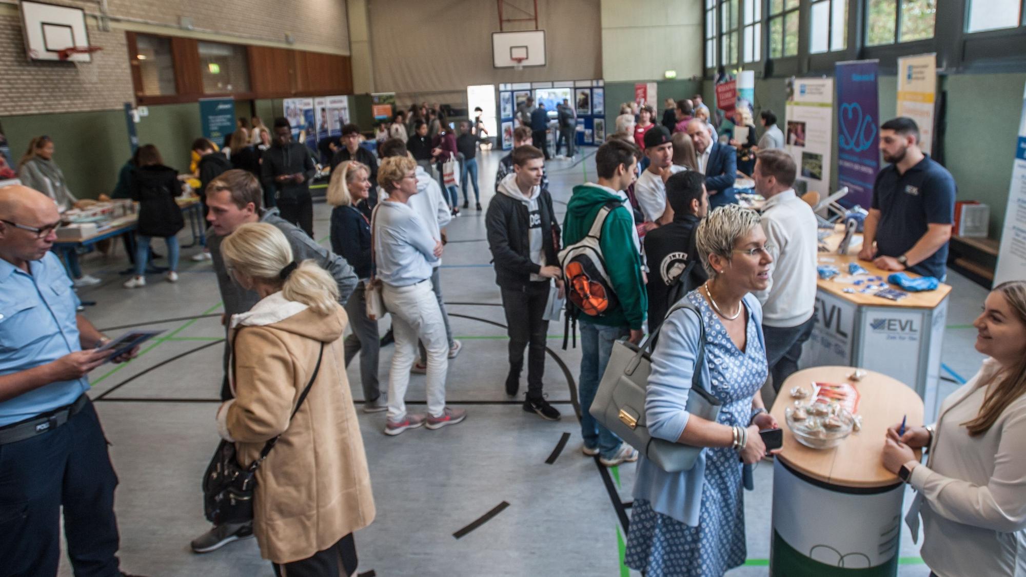Ausbilder und Azubis stehen am Tag der Bewerbung 2019 in der Sporthalle des Berufskollegs Opladen.