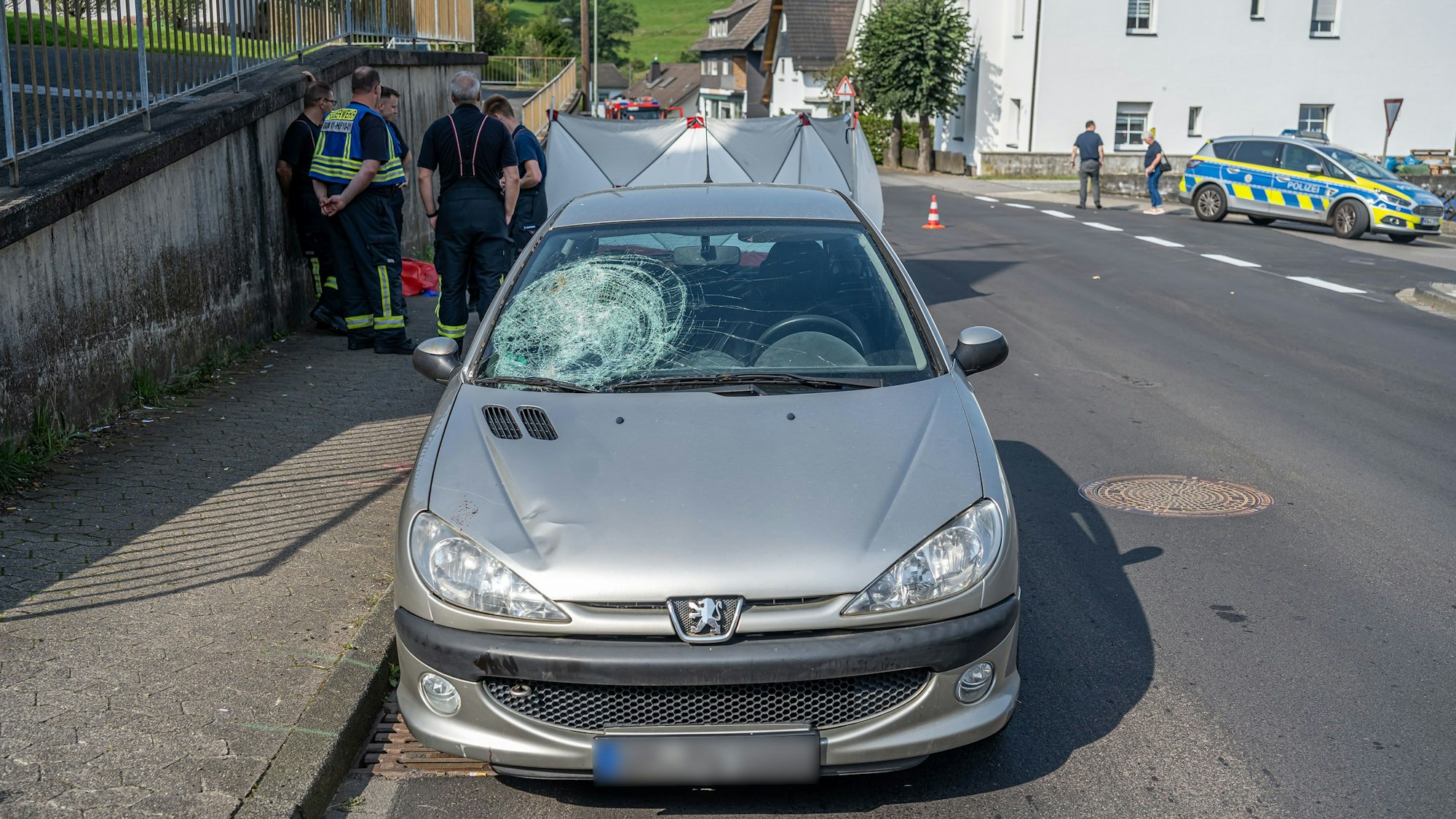 Ein Unfallwagen steht auf der Straße. Die Windschutzscheibe ist auf einer Seite eingedrückt.