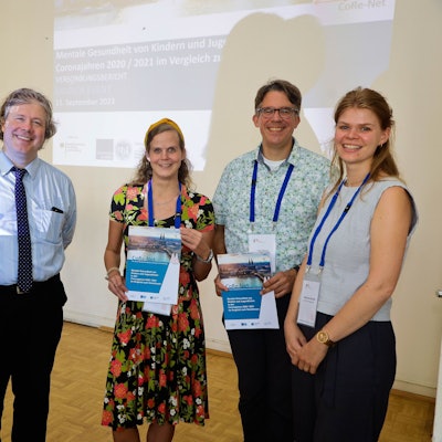 Fünf Personen stehen im Hauptgebäude der Uniklinik und lächeln in die Kamera.