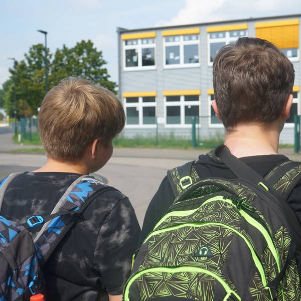 Das Bild zeigt zwei Schüler vor dem Schulgebäude der Gesamtschule.