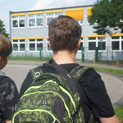 Das Bild zeigt zwei Schüler vor dem Schulgebäude der Gesamtschule.