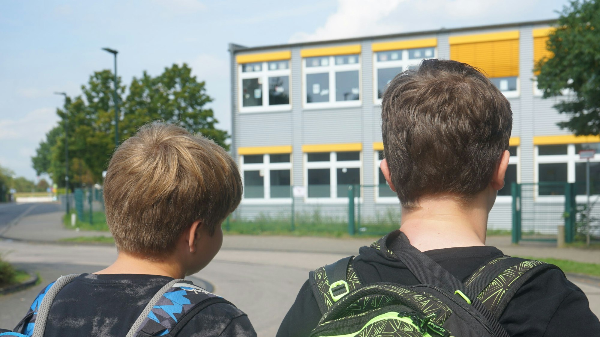 Das Bild zeigt zwei Schüler vor dem Schulgebäude der Gesamtschule.
