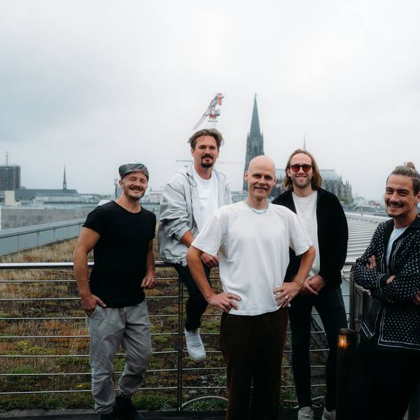 Die fünf Musiker stehen auf einer Terrasse, im Hintergrund ist der Dom zu sehen.