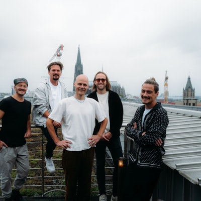 Die fünf Musiker stehen auf einer Terrasse, im Hintergrund ist der Dom zu sehen.