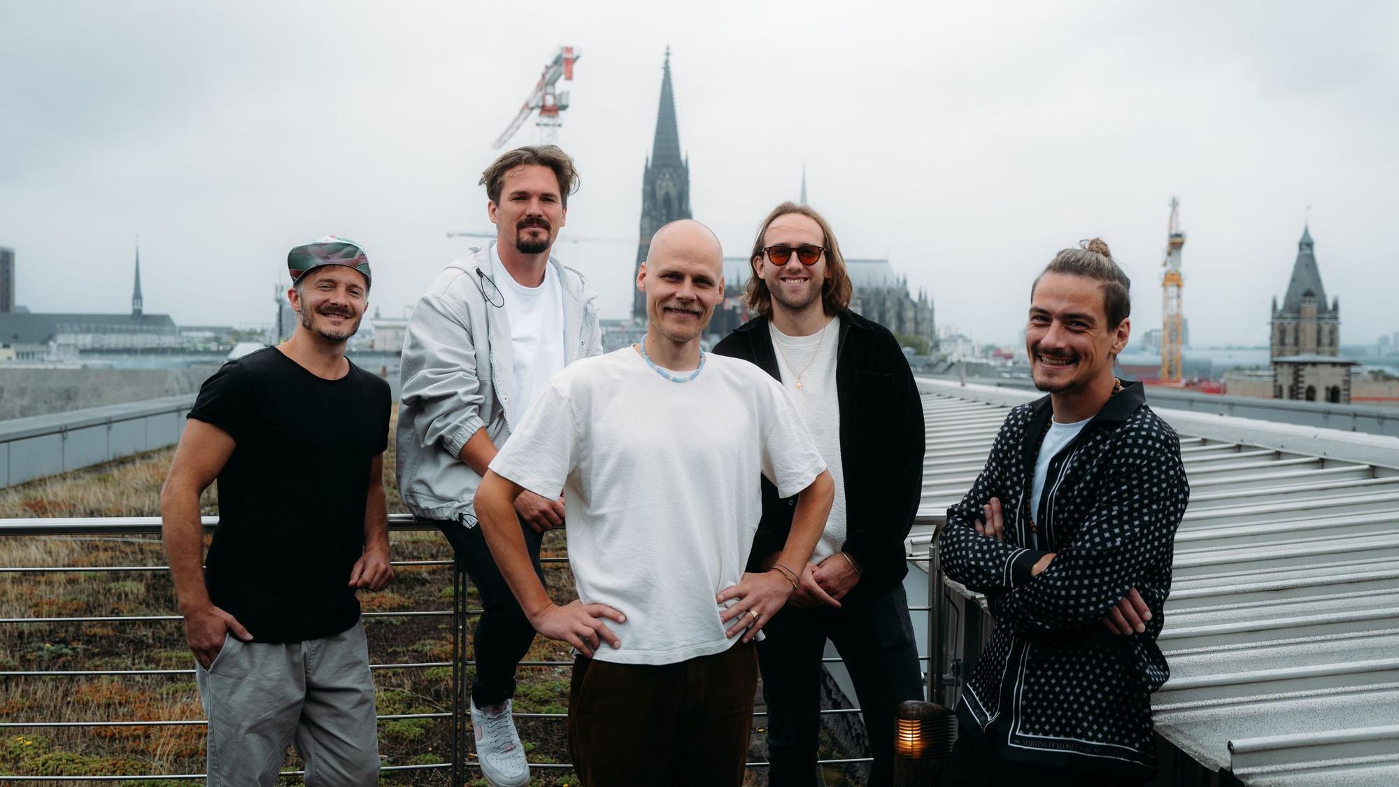Die fünf Musiker stehen auf einer Terrasse, im Hintergrund ist der Dom zu sehen.