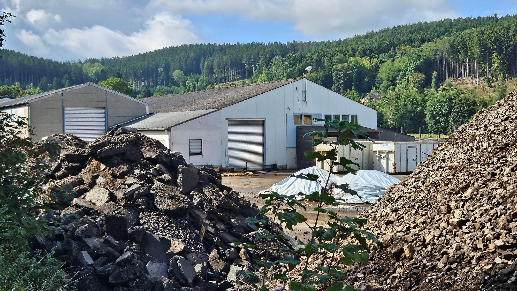 Zu sehen sind Schutthalden vor den Gebäuden des ehemaligen Sägewerks.