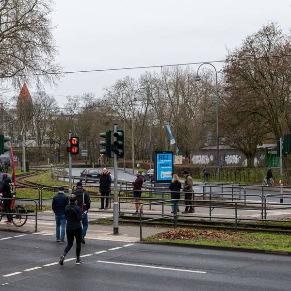 Passantinnen und Passanten überqueren einen Bahnübergang.