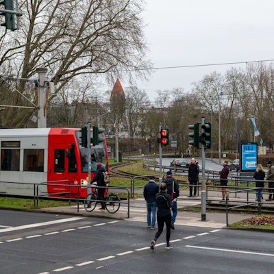 Passantinnen und Passanten überqueren einen Bahnübergang.