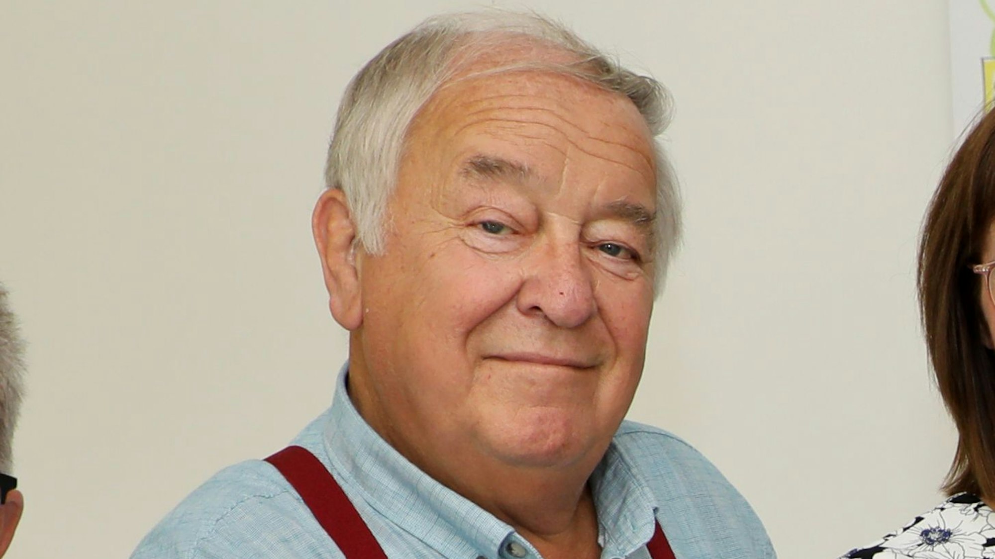 Ein Mann mit Hosenträgern schaut in die Kamera.