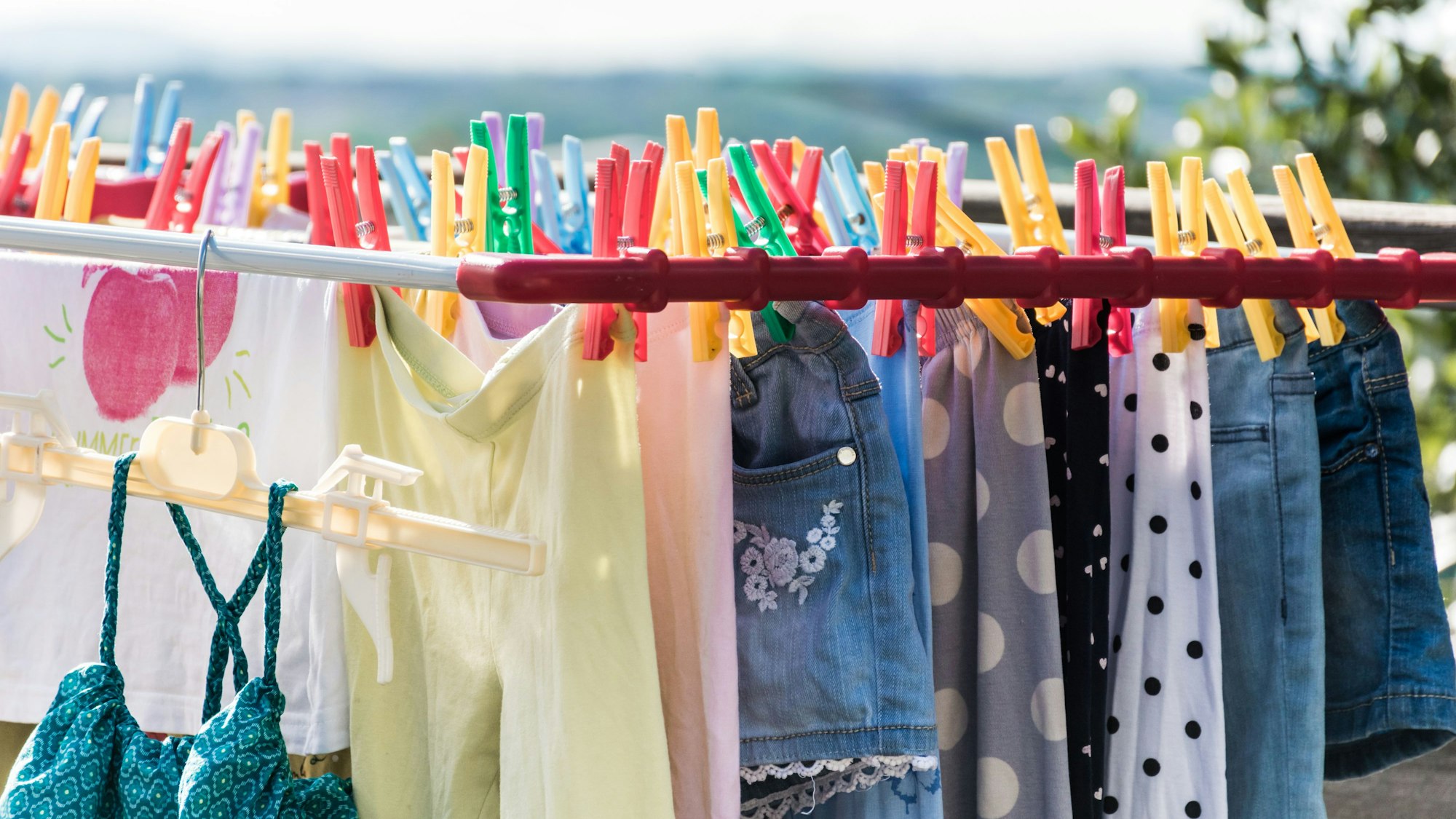 Wäsche trocknen draußen an der frischen Luft. Wäscheständer mit viel Wäsche und Wäscheklammern.