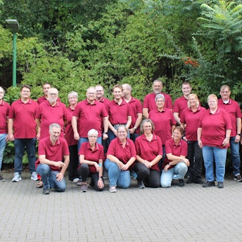 Rund 20 Mitglieder des Musikvereins Loope posieren in roten Polohemden.