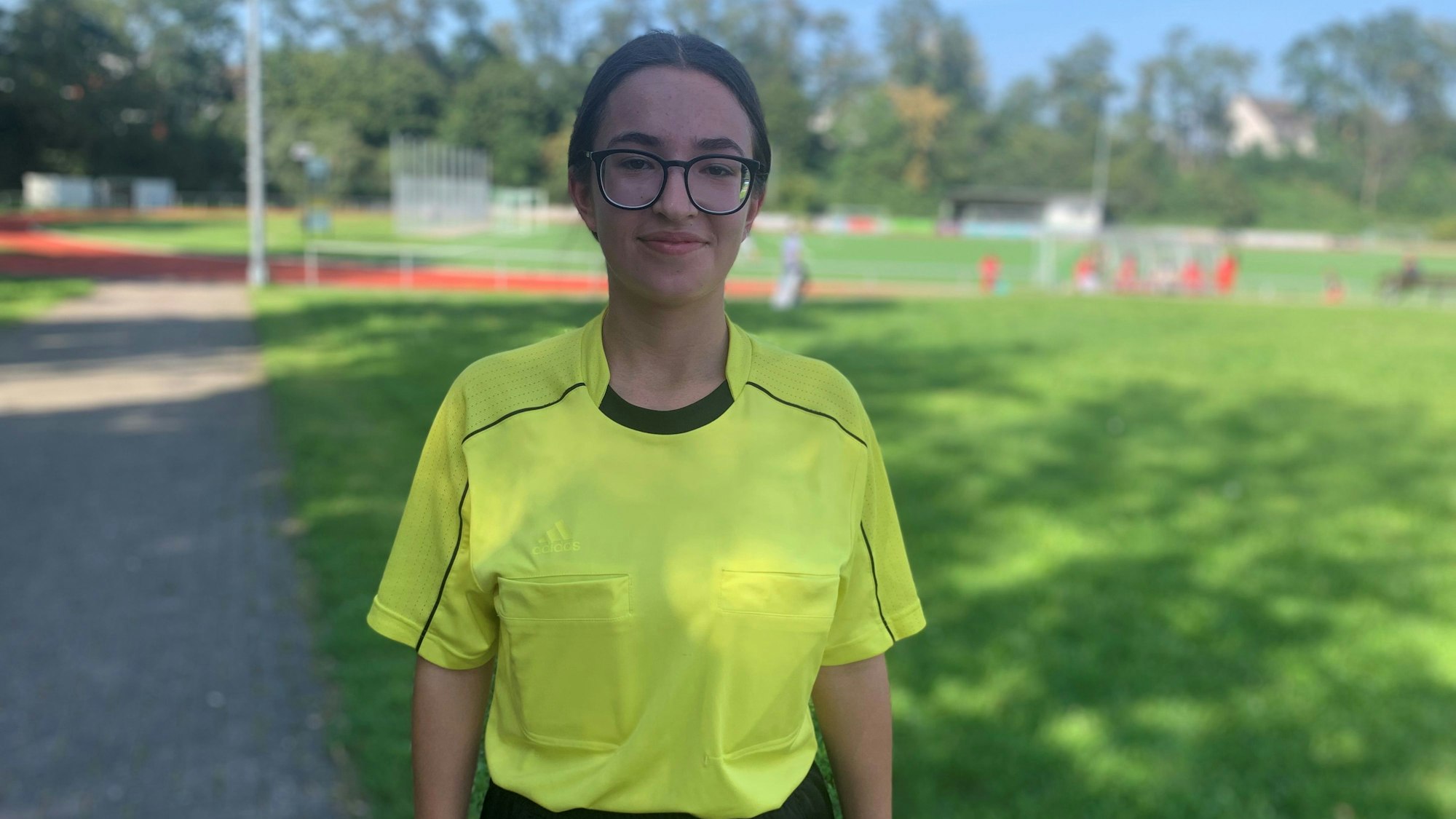 Ada Pur, Schiedsrichterin, trägt ein gelbes Shirt und guckt in die Kamera.