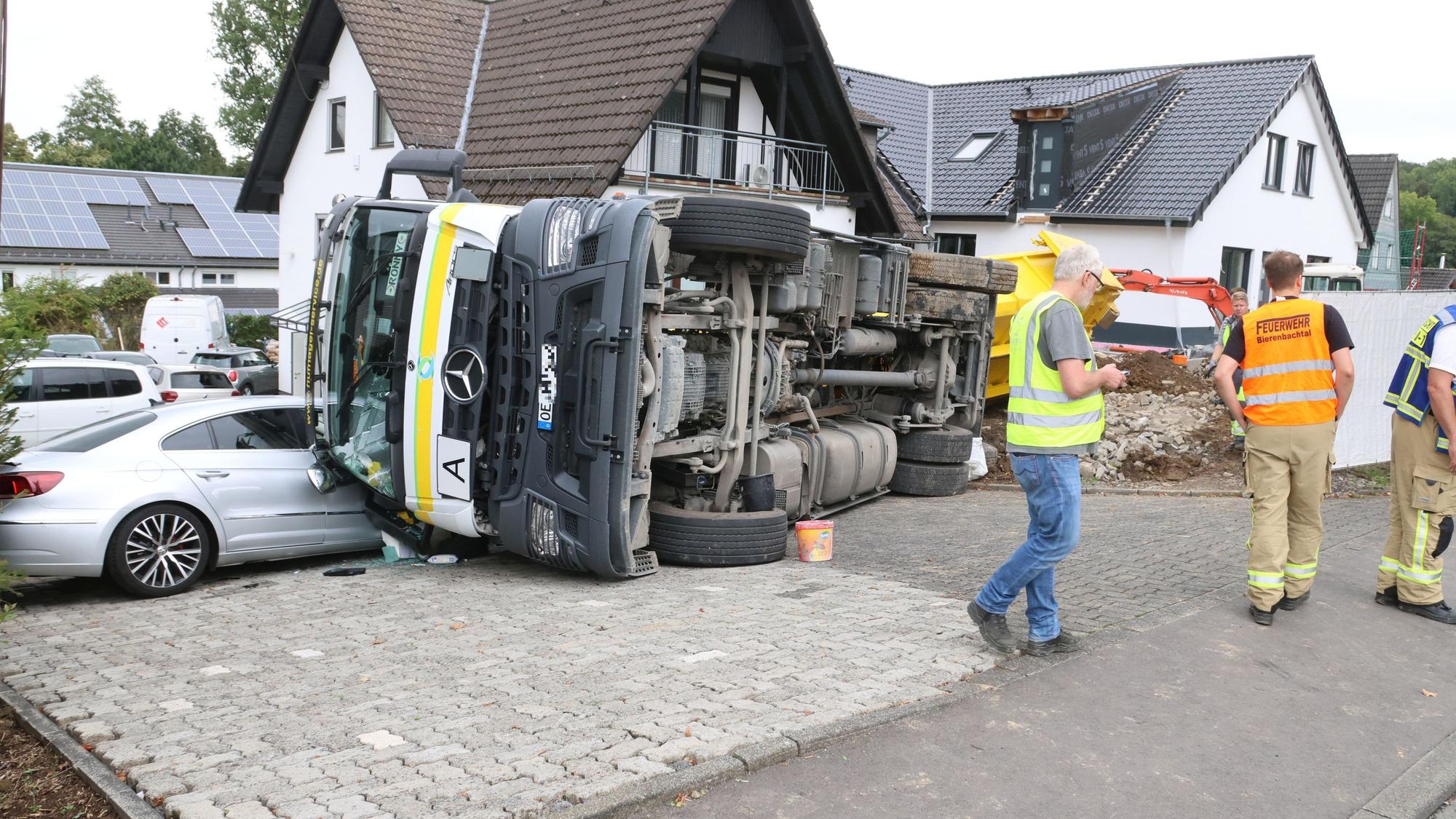 Ein Lkw liegt auf der Seite und berührt dabei ein geparktes Auto.