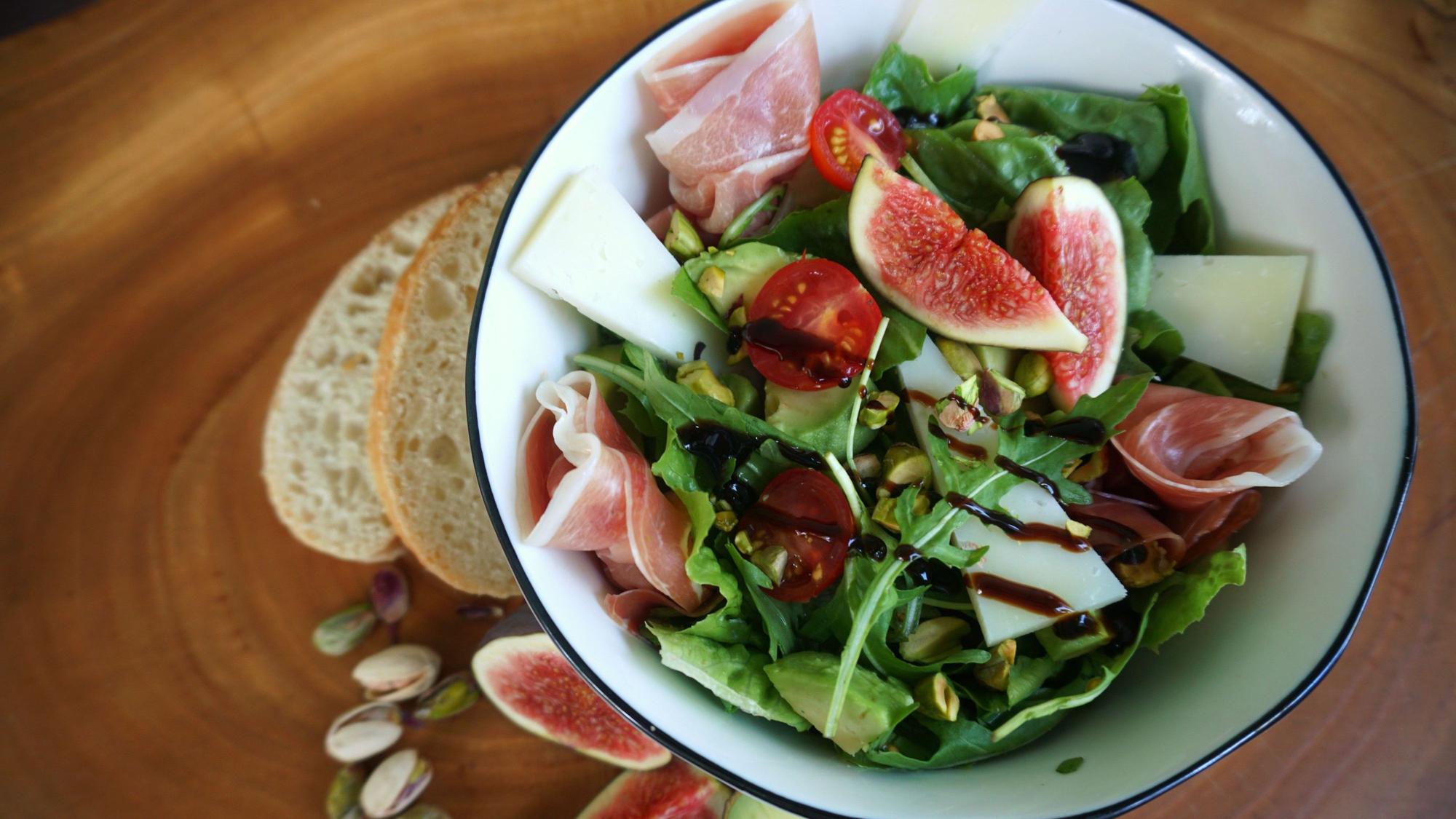 Römersalat kombiniert mit Käse, Schinken, gerösteten Pistazien und Feige