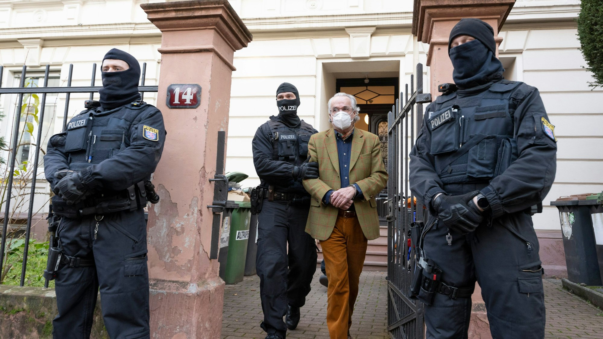 Bei einer Razzia gegen sogenannte „Reichsbürger“ führen vermummte Polizisten, nach der Durchsuchung eines Hauses Heinrich XIII Prinz Reuß (2.v.r.) zu einem Polizeifahrzeug. (Archivbild)