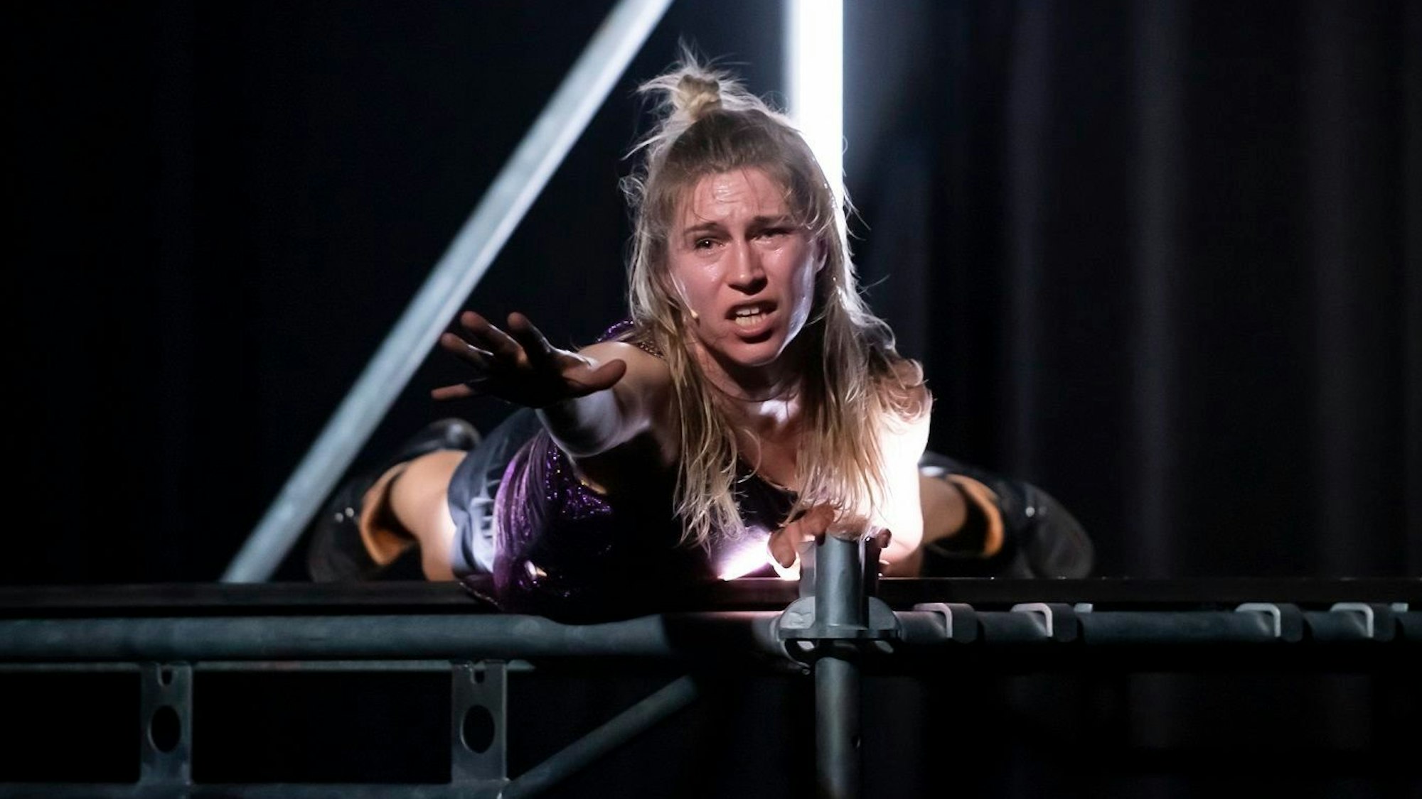 Mette Ingvartsen liegt in „The Dancing Public“ auf einer Bühne aus einem Gerüst und greift mit der Hand ins Leere.