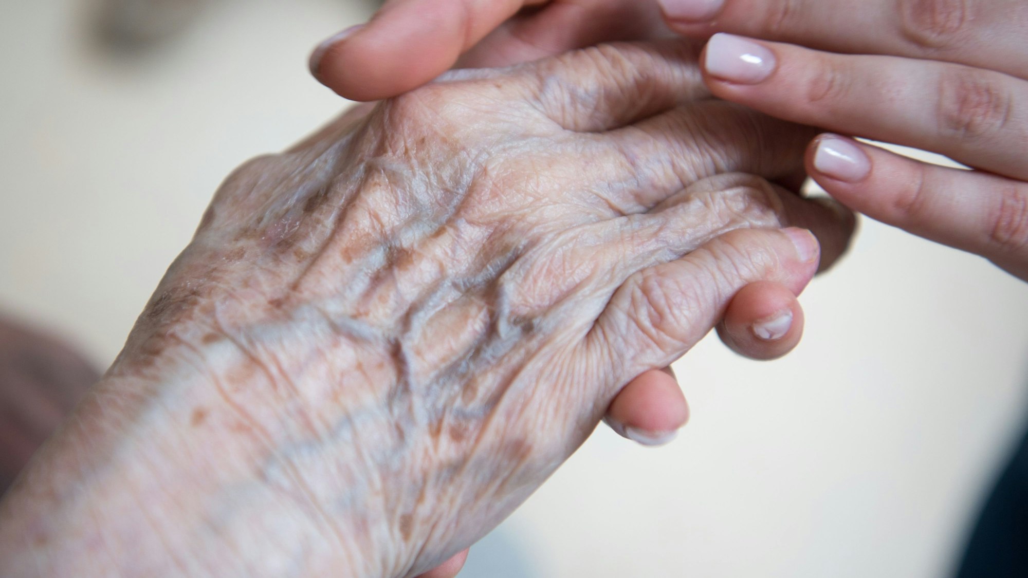 Eine Pflegerin hält die Hand einer Bewohnerin im Seniorenzentrum