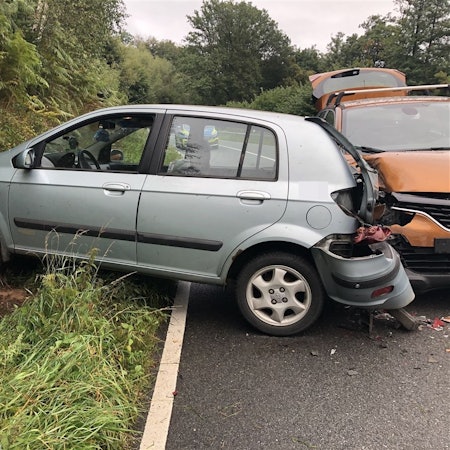 Zwei demolierte Autos stehen auf einer Straße.