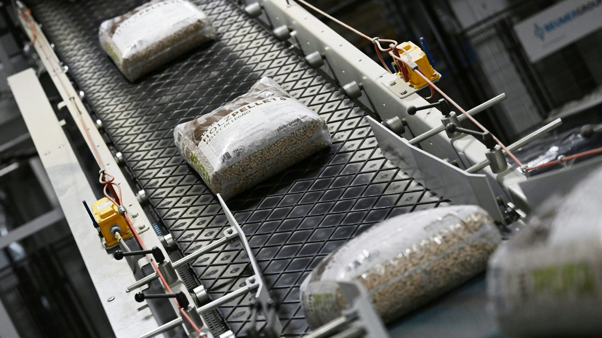 Fertige, in Säcke abgepackte Holzpellets laufen in einem Sägewerk über das Förderband.
