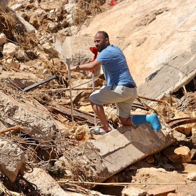Ein Mann steigt an Krücken über Trümmer.