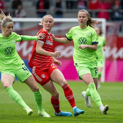 Die Wolfsburgerinnen Kathrin Hendrich (l.) und Lynn Wilms (r.) und Münchens Lea Schüller kämpfen um den Ball.