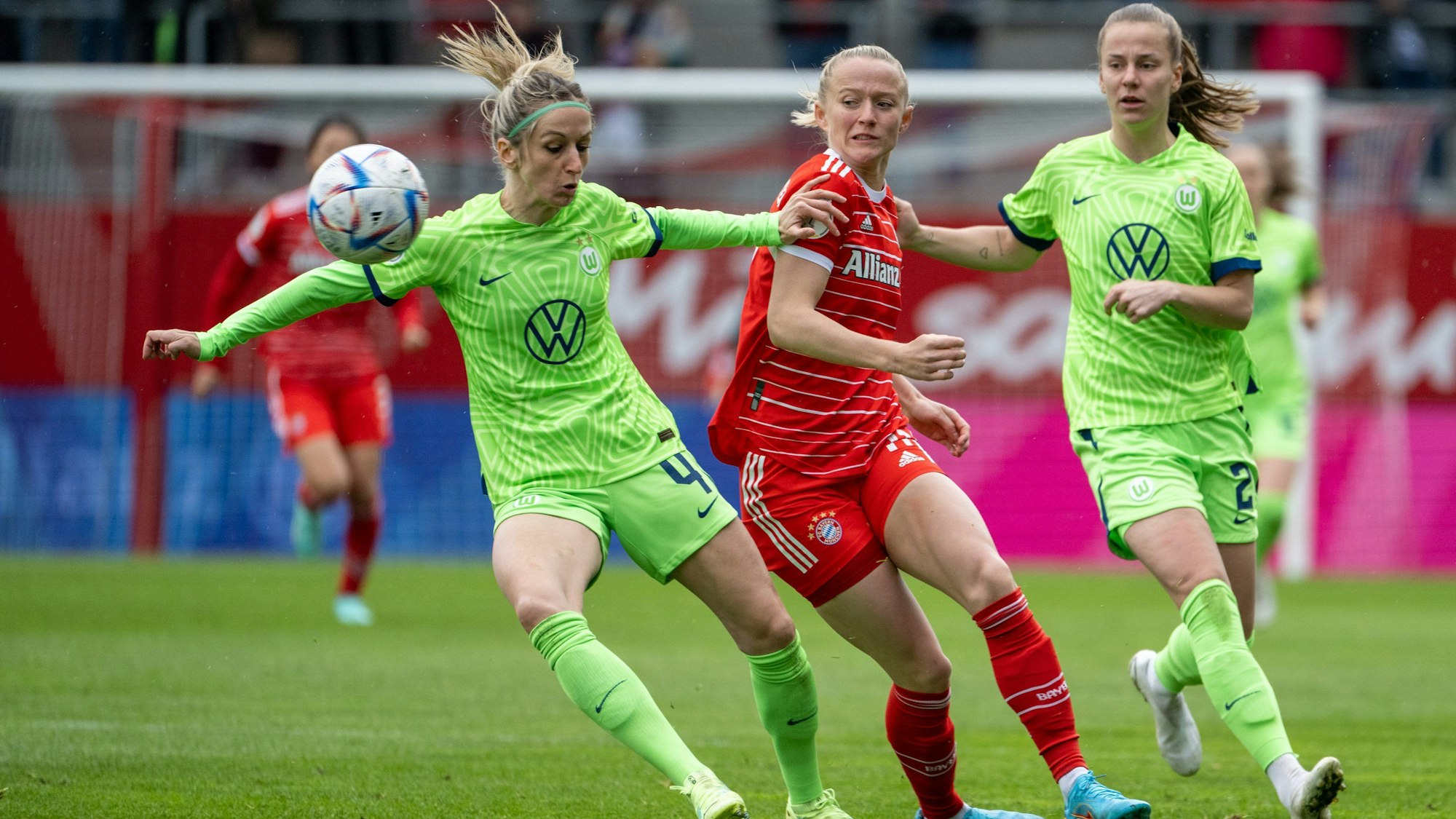 Die Wolfsburgerinnen Kathrin Hendrich (l.) und Lynn Wilms (r.) und Münchens Lea Schüller kämpfen um den Ball.