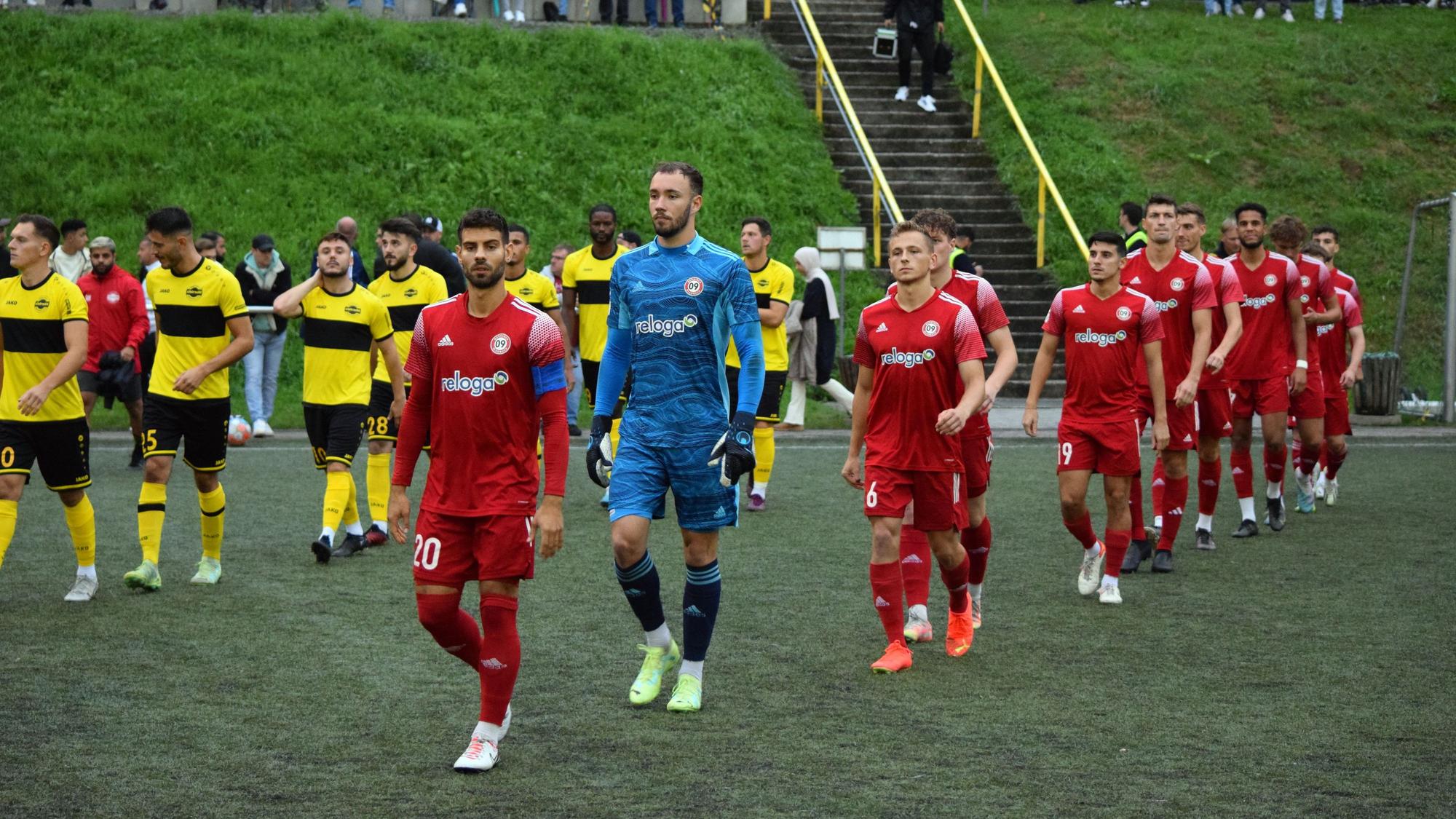 Zwei Mannschaften beim Einlauf vor einem Fußballspiel.