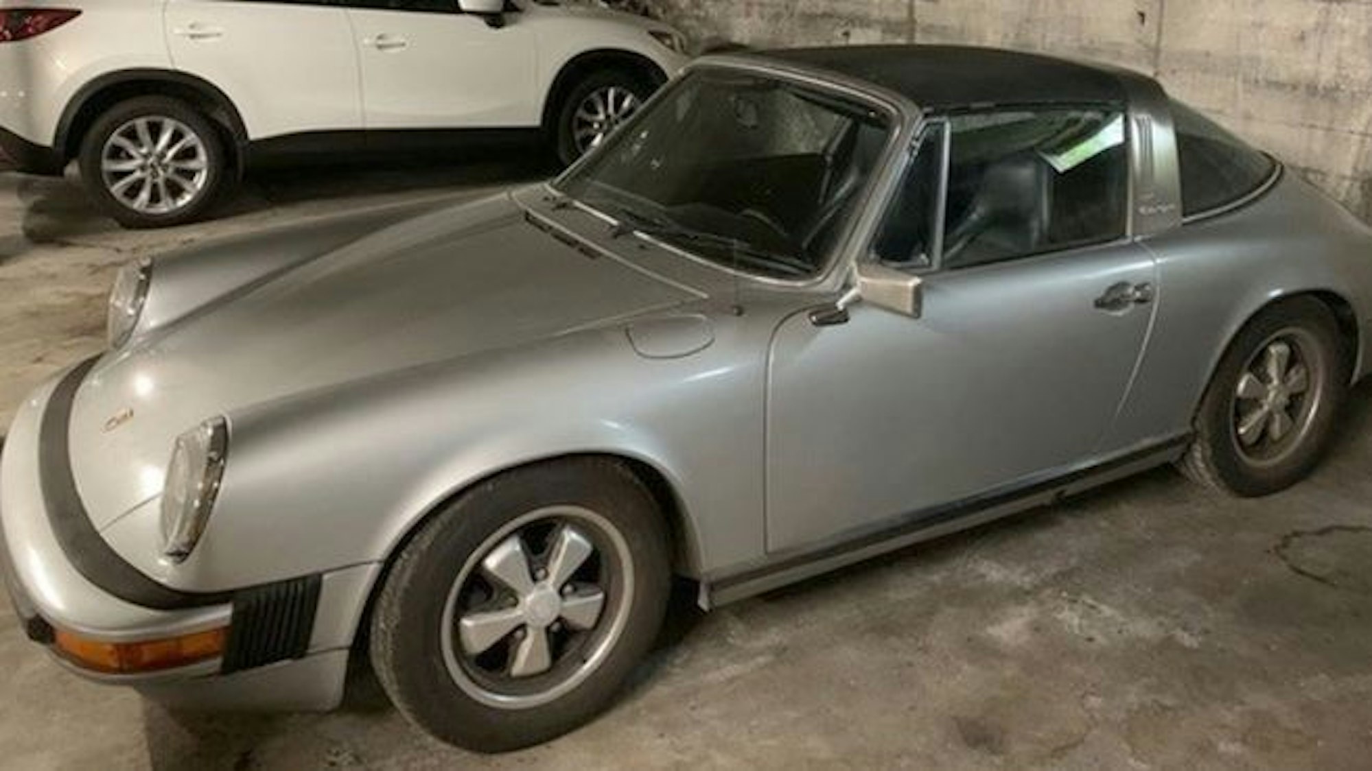 Ein grauer Porsche steht in einer Tiefgarage.