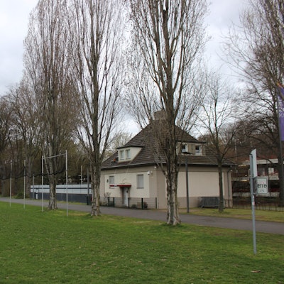 Zu sehen ist das einzige Gebäude von 1923, das im Sportpark Müngersdorf bis heute erhalten geblieben ist: das Diensthäuschen an der Aachener Straße.