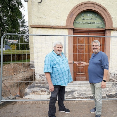 Zwei Männer stehen vor dem mit einem Bauzaun abgesperrten Portal der Kirche in Schleiden.