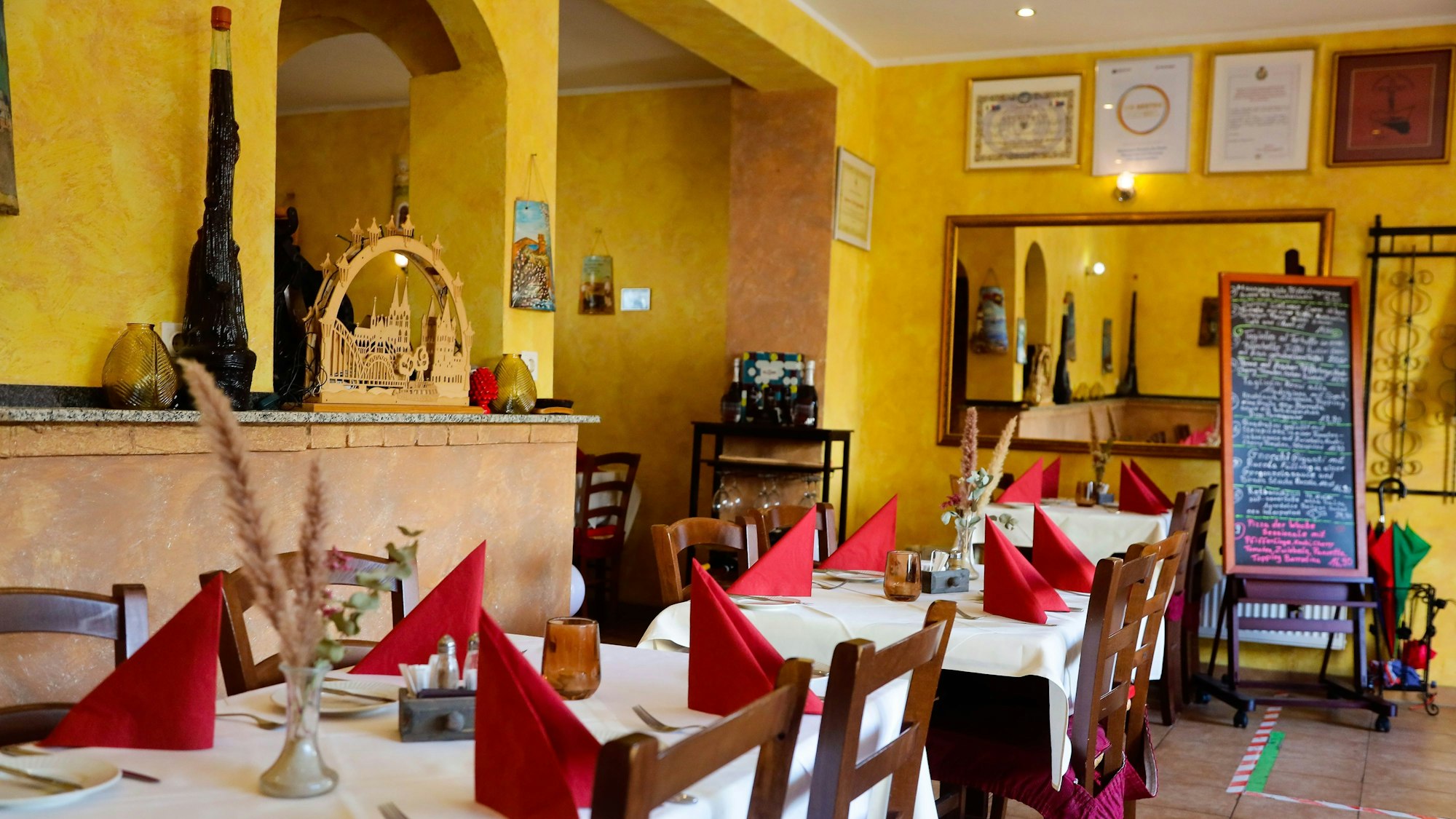 Blick in den gelb gestrichenen Gastraum mit gedeckten Tischen im Da Mario.