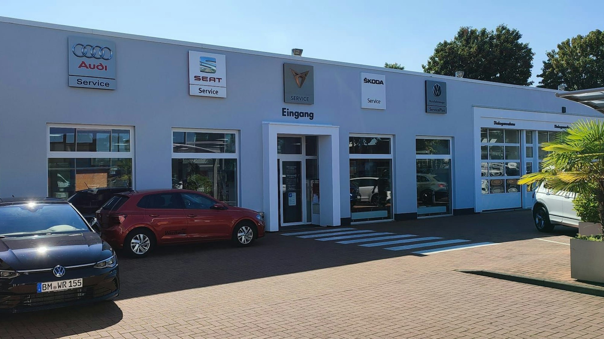 Das Foto zeigt ein Gebäude mit einem VW-Logo, davor parken Autos.