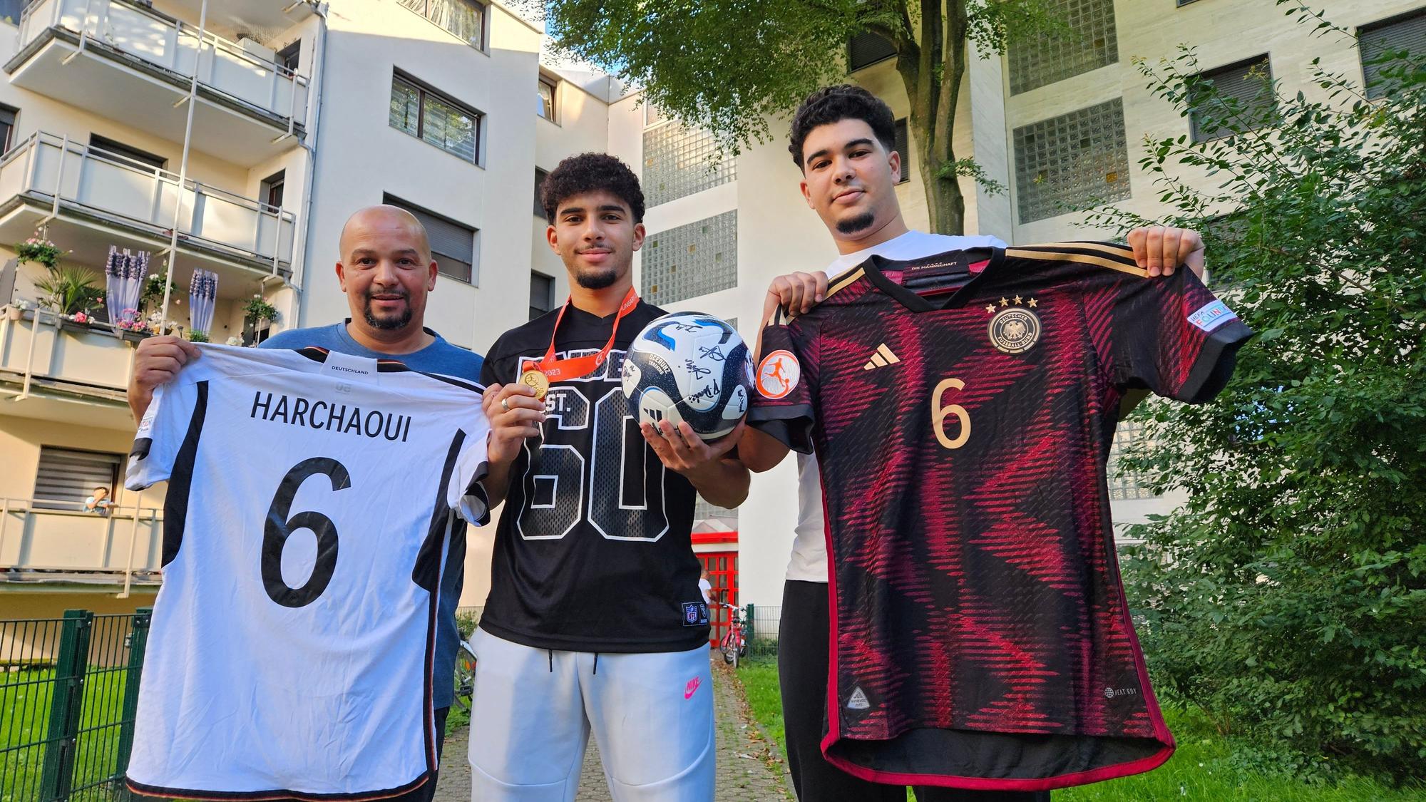 Auf dem Foto halten Fayssal, sein Vater Mohammed und Bruder Imad Trikots in die Kamera.