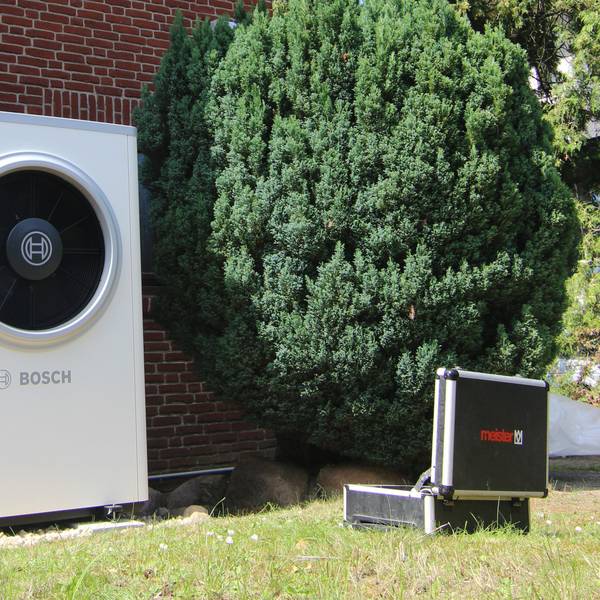 PRODUKTION - 11.08.2023, Berlin: Eine gerade installierte Wärmepumpe von Bosch sowie ein Handwerker-Koffer sind vor einer Doppelhaushälfte zu sehen. (zu dpa «Ausblick auf die Bundestagsentscheidung zum sogenannten Heizungsgesetz nach der Sommerpause») Foto: Doreen Garud/dpa +++ dpa-Bildfunk +++