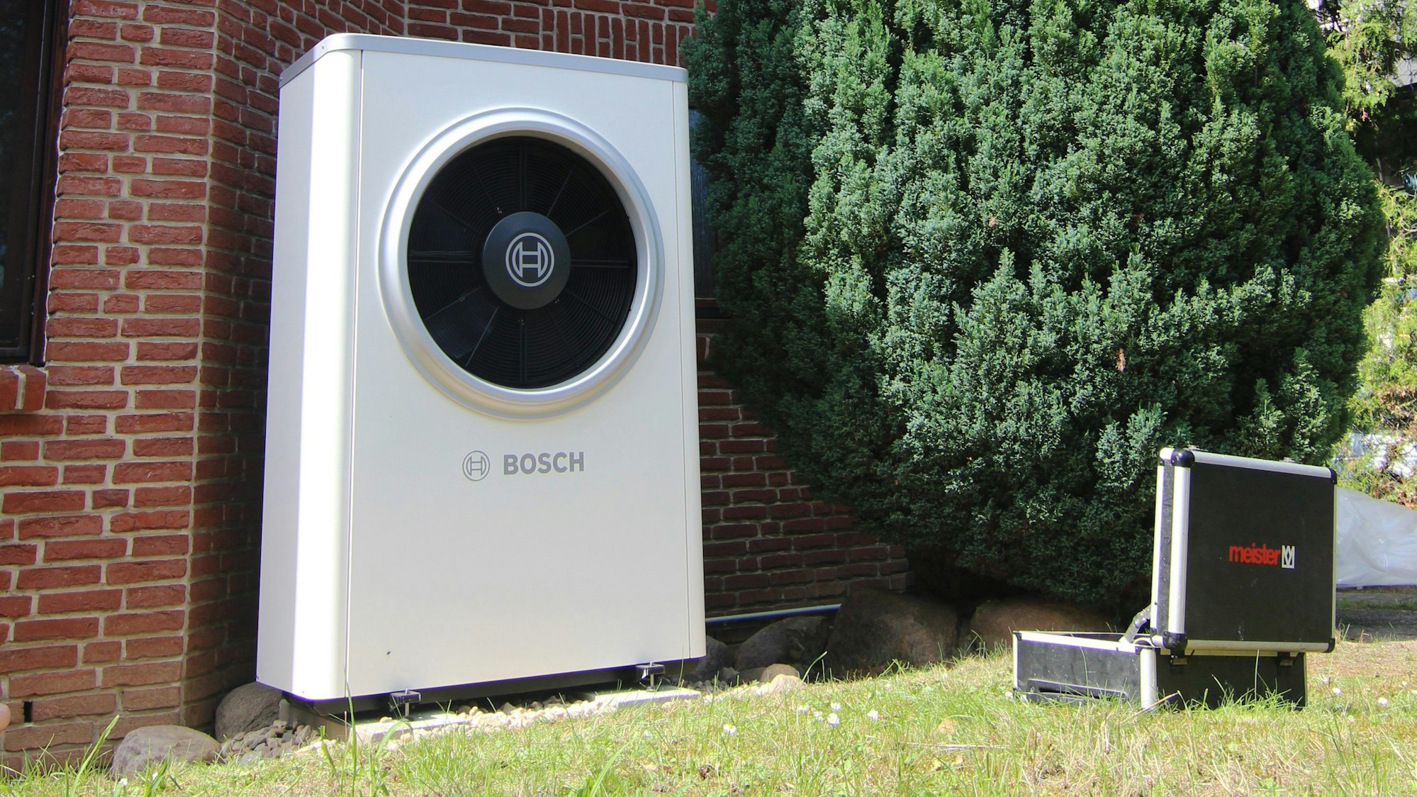 PRODUKTION - 11.08.2023, Berlin: Eine gerade installierte Wärmepumpe von Bosch sowie ein Handwerker-Koffer sind vor einer Doppelhaushälfte zu sehen. (zu dpa «Ausblick auf die Bundestagsentscheidung zum sogenannten Heizungsgesetz nach der Sommerpause») Foto: Doreen Garud/dpa +++ dpa-Bildfunk +++