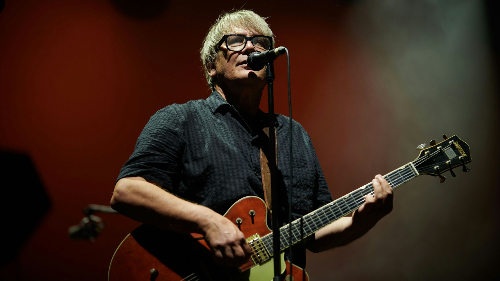 Element of Crime live 2023: Sänger Sven Regener steht am Mikrofon und spielt E-Gitarre.