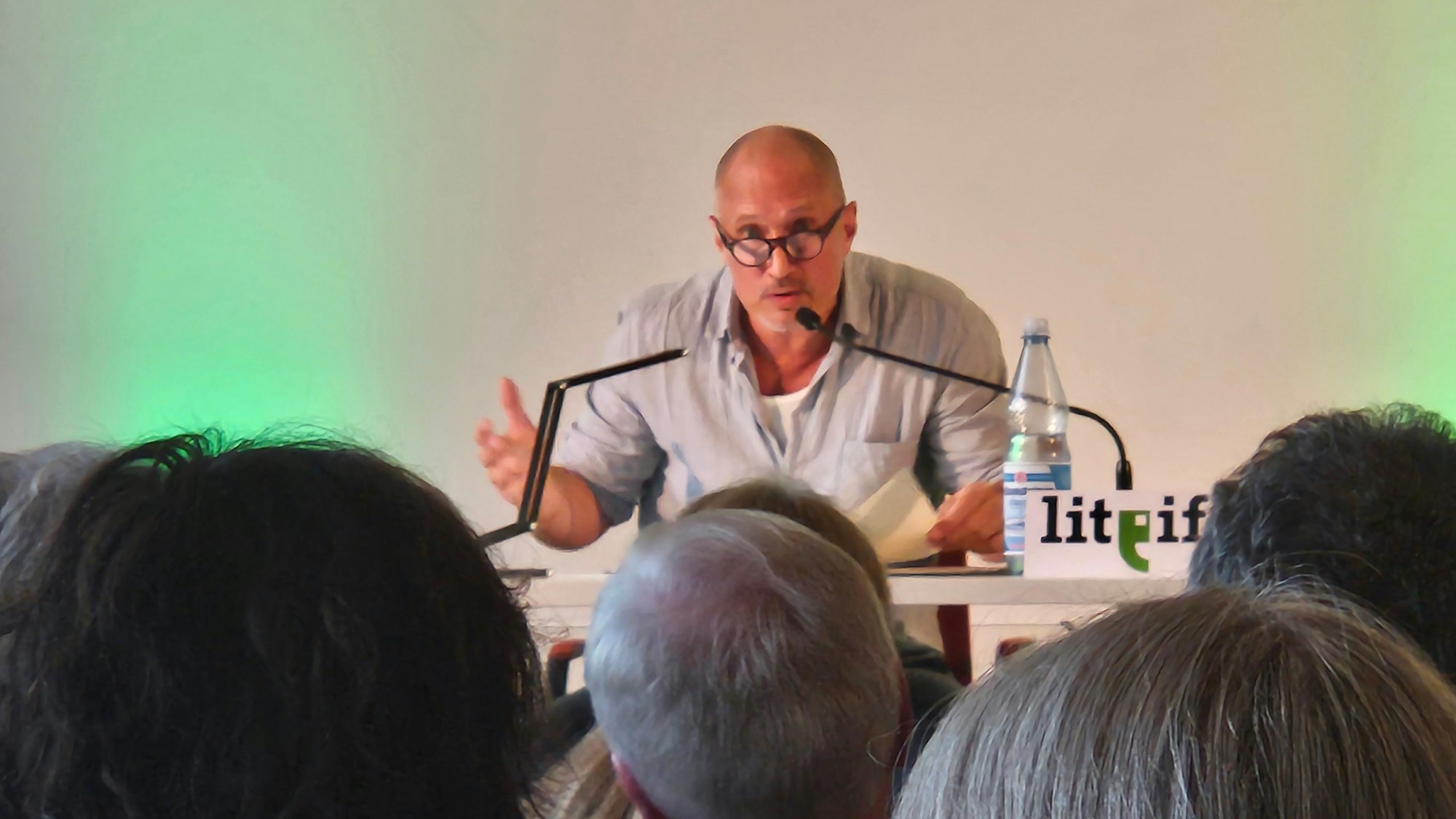 Schauspieler und Autor Benno Fürmann sitzt an einem Tisch vor Zuhörern.