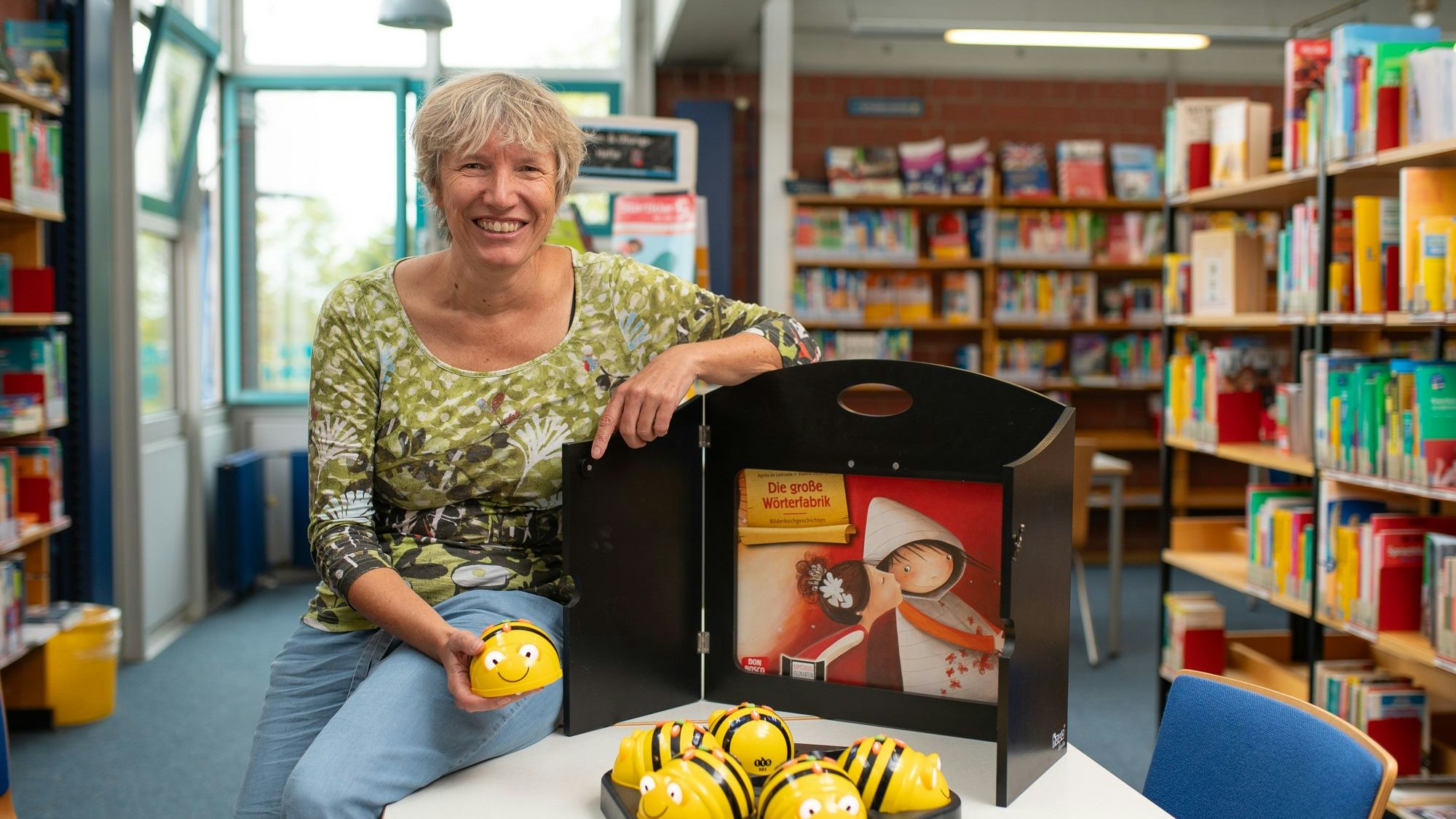 Das Bild zeigt die Büchereileiterin mit Mini-Mobotern in Form von Bienen.