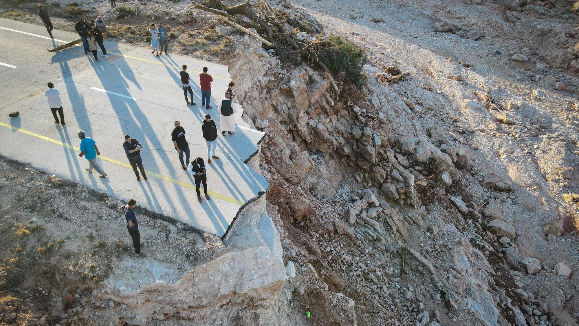 Menschen stehen an einer durch die Überschwemmungen zerstörten Straße im Osten Libyens nahe der Hafenstadt Darna, wo 20.000 Tote befürchtet werden.
