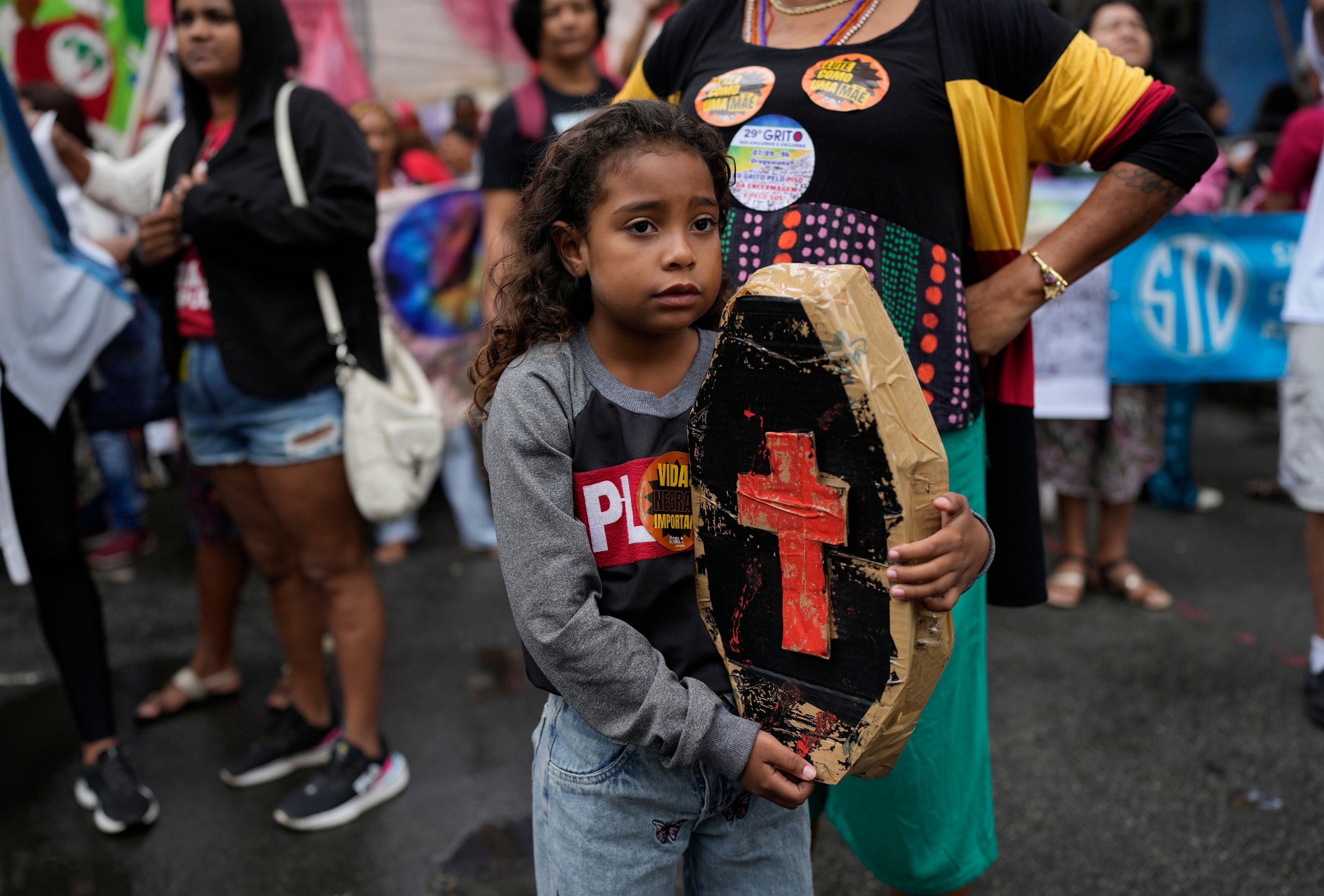 A child holds a small, mock coffin as relatives of people killed in police operations, against suspected drug traffickers and thieves in favelas, attend a march coined "The scream of the excluded" to call for a more democratic nation and to put an end to economic inequality, on Independence Day in Rio de Janeiro, Brazil, Thursday, Sept. 7, 2023. (AP Photo/Silvia Izquierdo)